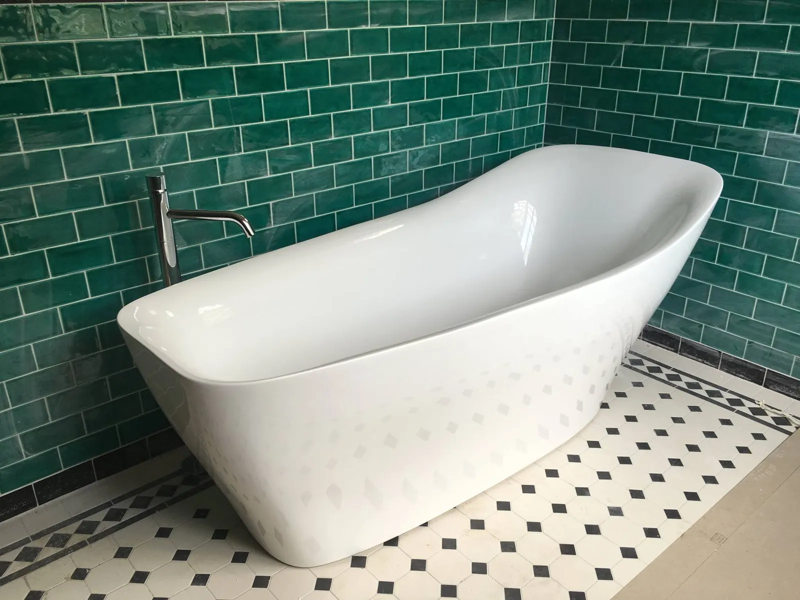 Freestanding bath against green subway tiles with period floor tiles