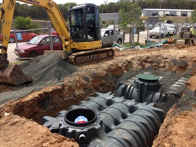 Excavator installing underground tanks on a commercial site